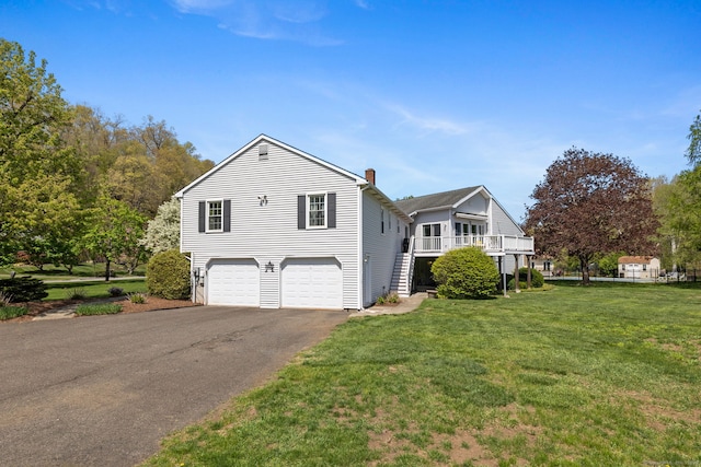 view of front of house featuring a front yard, a chimney, a garage, and aphalt driveway