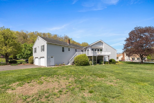 back of property with a chimney, driveway, a garage, stairs, and a deck