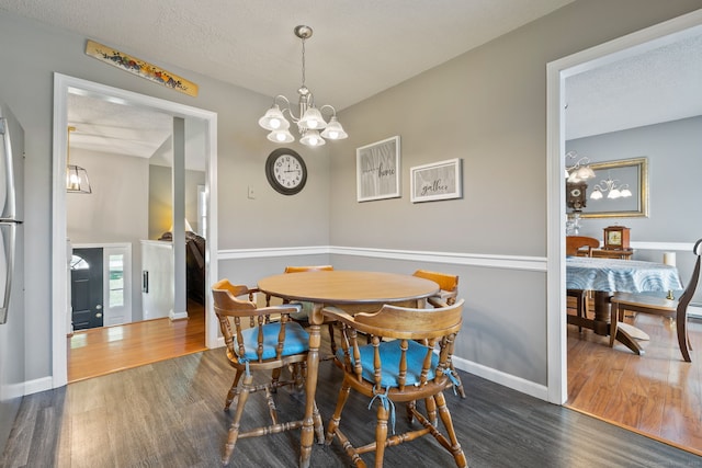 dining area featuring wood finished floors, baseboards, and a notable chandelier