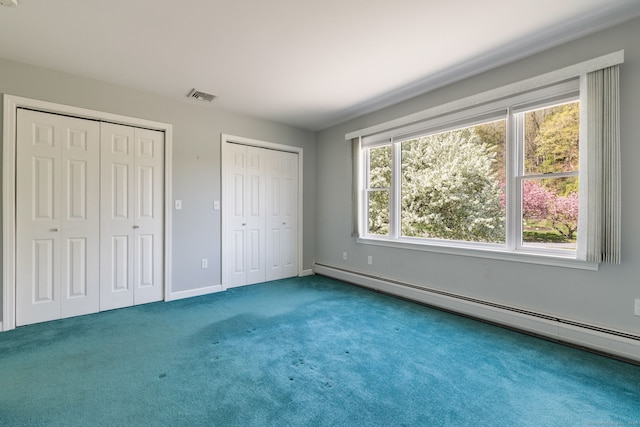 unfurnished bedroom with carpet flooring, two closets, visible vents, baseboards, and a baseboard heating unit