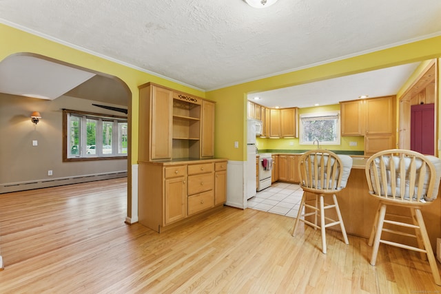 kitchen with a baseboard heating unit, light wood-style flooring, plenty of natural light, white appliances, and ornamental molding