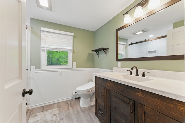bathroom featuring a baseboard heating unit, wainscoting, wood finished floors, toilet, and a shower with shower door