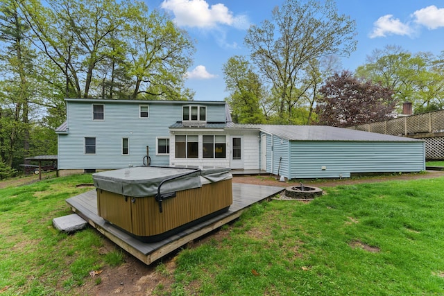 rear view of house featuring a hot tub, a yard, an outdoor fire pit, metal roof, and a deck