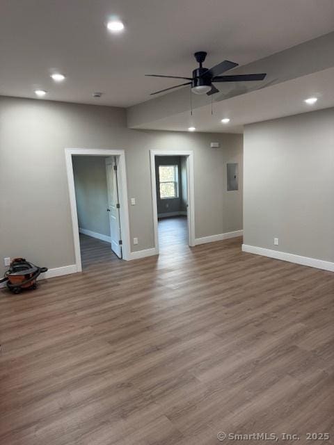 unfurnished room featuring ceiling fan, baseboards, wood finished floors, recessed lighting, and electric panel