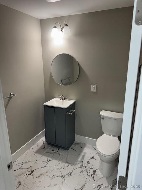bathroom featuring baseboards, toilet, vanity, and marble finish flooring
