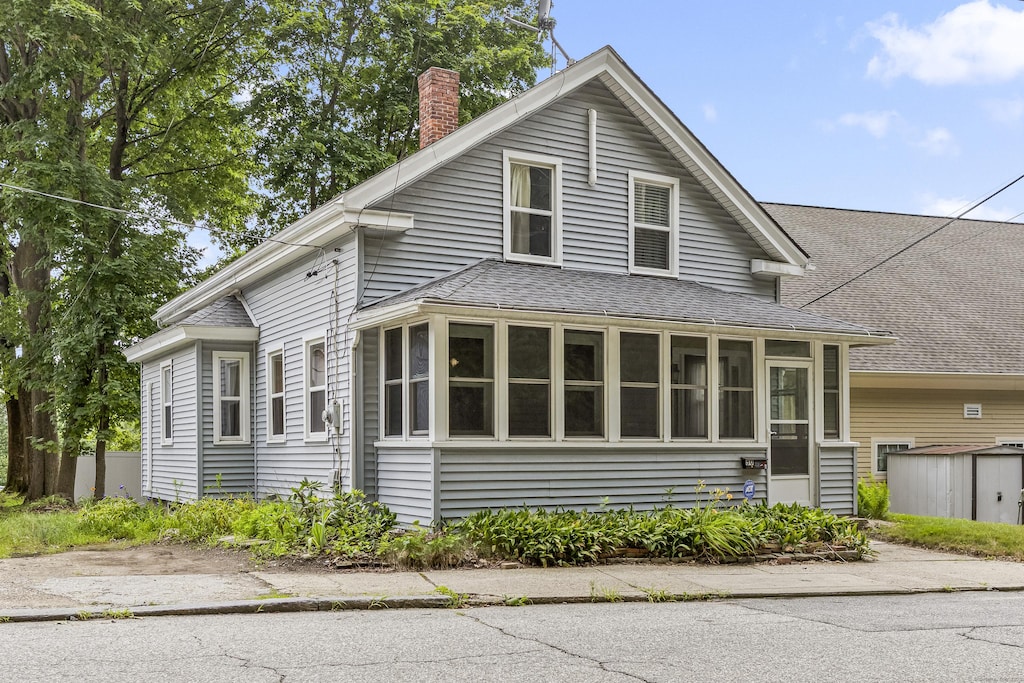 30 School St, Putnam, CT 06260 - view of front of property with a chimney, roof with shingles, a storage shed, and a sunroom