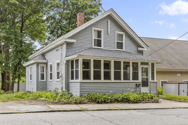 30 School St, Putnam, CT 06260 - view of front of property with a chimney, roof with shingles, a storage shed, and a sunroom