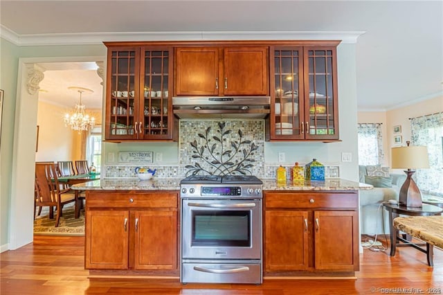 kitchen with stainless steel range with gas stovetop, ornamental molding, under cabinet range hood, and wood finished floors