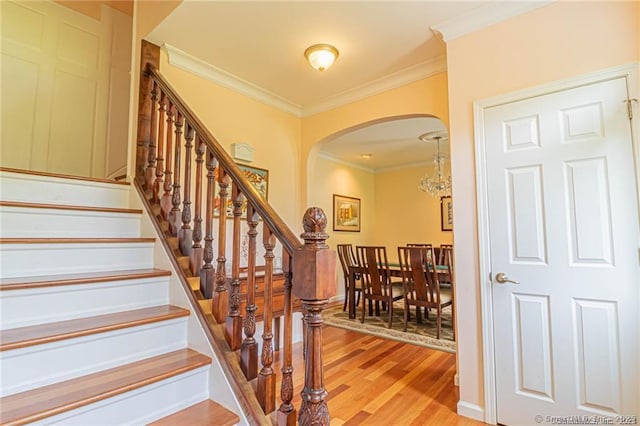 stairs featuring arched walkways, ornamental molding, and wood finished floors