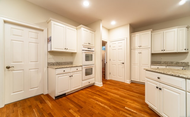 42 N Woods Rd, Hamden, CT 06518 - kitchen with double oven, wood finished floors, white cabinets, recessed lighting, and light stone countertops