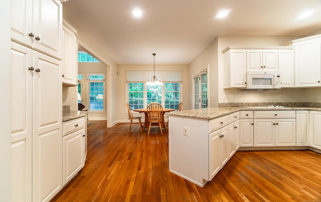 42 N Woods Rd, Hamden, CT 06518 - kitchen featuring white microwave, a peninsula, white cabinetry, dark wood-type flooring, and hanging light fixtures