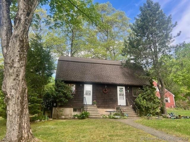view of front of home featuring entry steps, a shingled roof, and a front yard