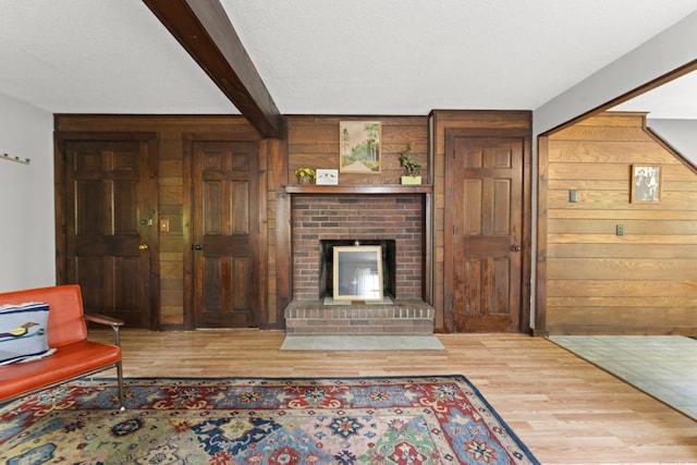 63 Schofield Rd Apt 60, Willington, CT 06279 - living room with wood walls, wood finished floors, beamed ceiling, and a brick fireplace
