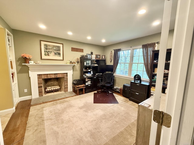 office featuring baseboards, a fireplace, recessed lighting, and wood finished floors
