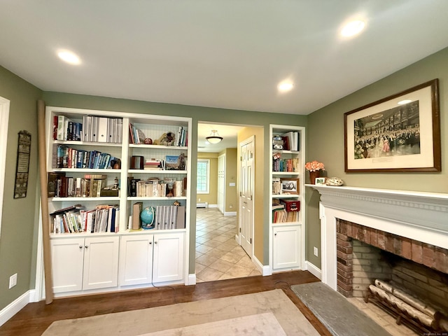sitting room featuring built in features, baseboards, a brick fireplace, and recessed lighting
