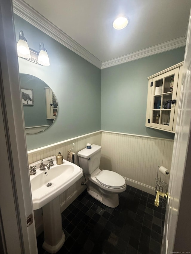 bathroom with a sink, toilet, ornamental molding, tile patterned flooring, and wainscoting