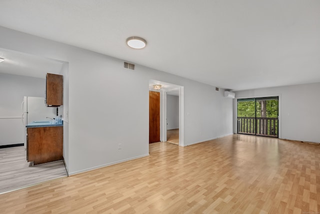 40 Woodsedge Dr Apt 2C, Newington, CT 06111 - unfurnished living room with light wood finished floors, an AC wall unit, and baseboards