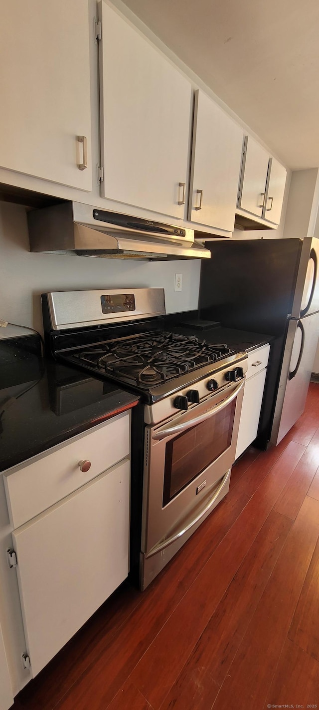 kitchen featuring dark wood-style flooring, stainless steel gas stove, dark countertops, under cabinet range hood, and white cabinets