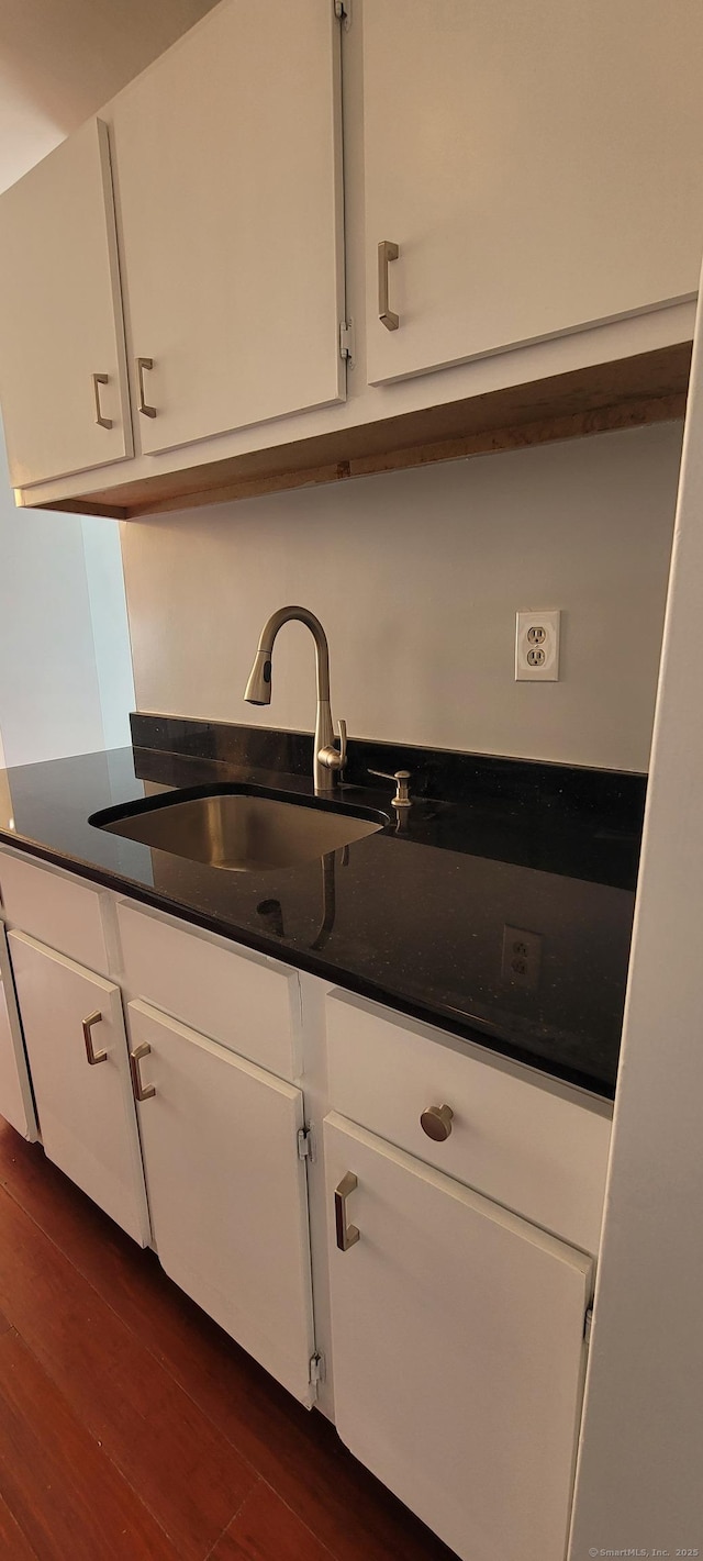 kitchen with a sink, dark countertops, and white cabinetry