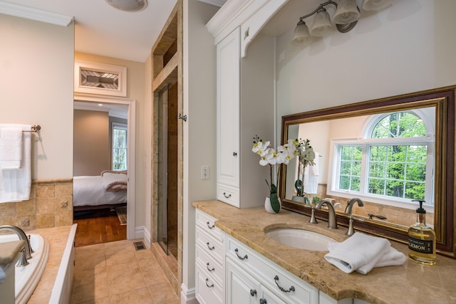 ensuite bathroom with plenty of natural light, vanity, a stall shower, and tiled bath