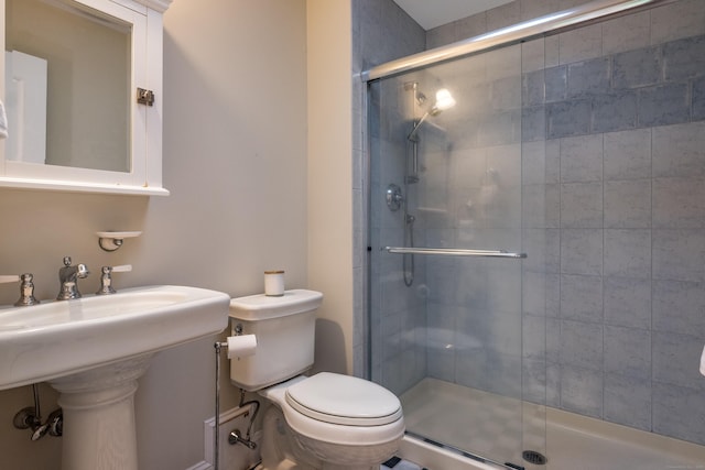 bathroom with a stall shower, toilet, and a sink