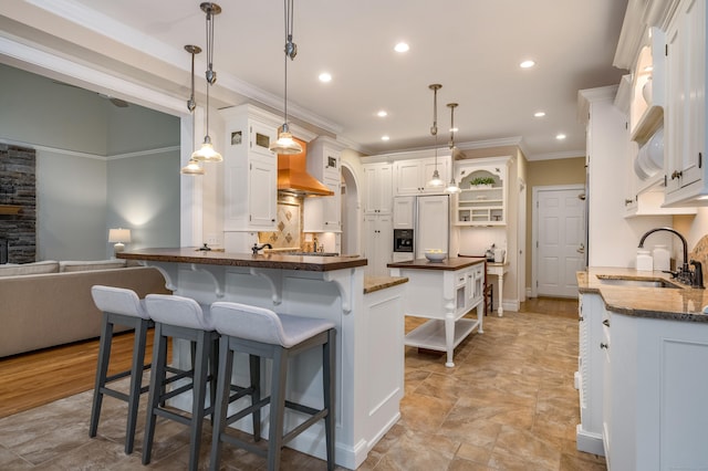 kitchen featuring open shelves, a sink, a breakfast bar area, white cabinetry, and ornamental molding