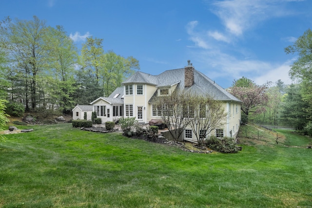 rear view of property featuring a chimney and a yard