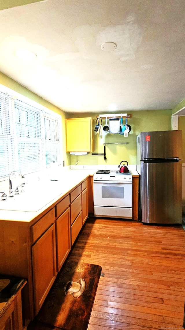 243 Bridge St, Groton, CT 06340 - kitchen with freestanding refrigerator, white gas range, light wood-style floors, a sink, and light countertops