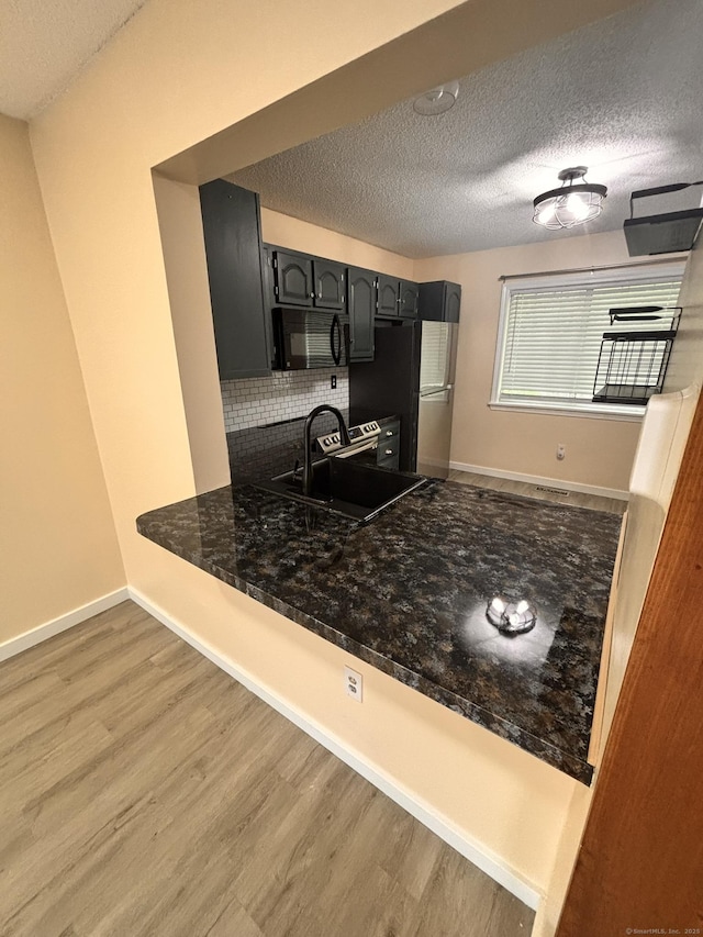 109 Bucks Hill Rd Unit 12, Waterbury, CT 06704 - kitchen featuring black microwave, wood finished floors, a peninsula, a textured ceiling, and baseboards
