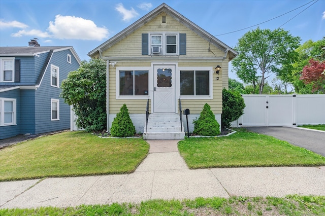 bungalow-style house featuring fence, cooling unit, a gate, and a front lawn