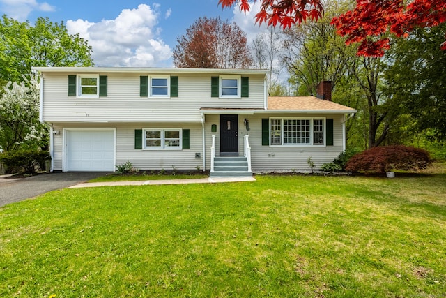 split level home featuring a garage, a front lawn, aphalt driveway, and a chimney