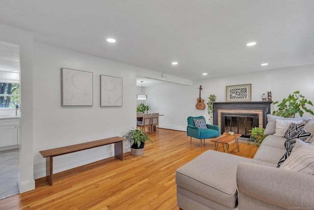 living room featuring a brick fireplace, recessed lighting, and light wood finished floors