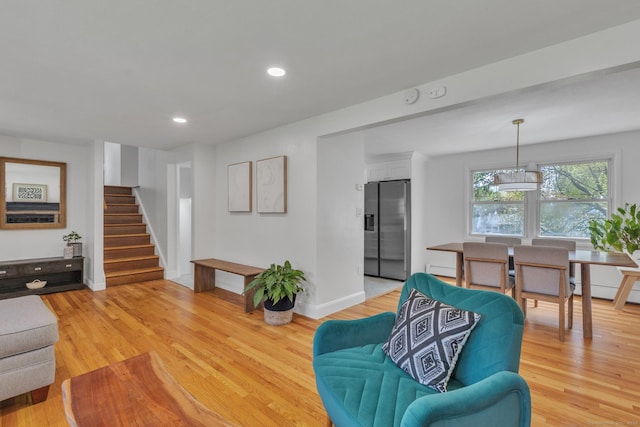 living room featuring light wood-style floors, stairs, recessed lighting, baseboards, and a baseboard radiator