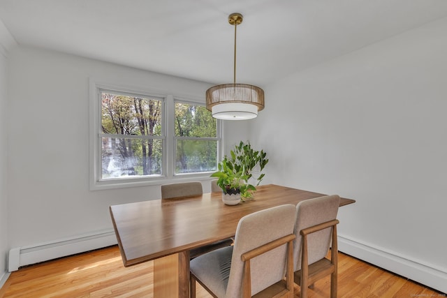 dining area featuring a baseboard heating unit and light wood finished floors