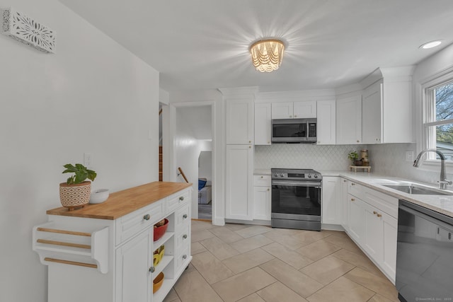 kitchen featuring a sink, appliances with stainless steel finishes, backsplash, and white cabinets