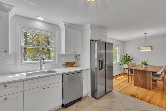 kitchen featuring stainless steel appliances, light tile patterned flooring, white cabinetry, and a sink