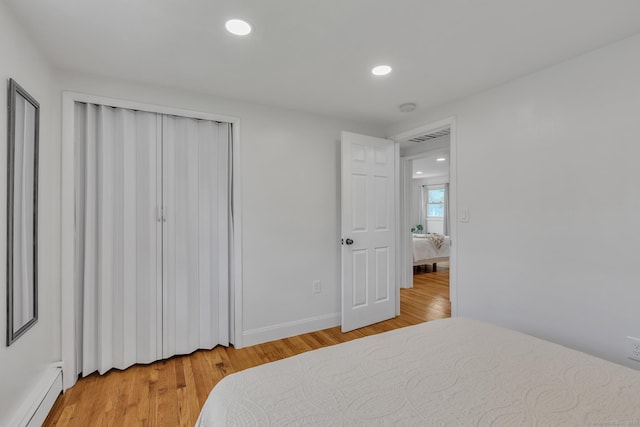 bedroom with baseboards, a closet, a baseboard heating unit, light wood finished floors, and recessed lighting