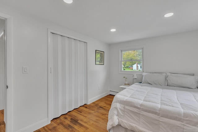 bedroom with recessed lighting, baseboards, a baseboard heating unit, and wood finished floors