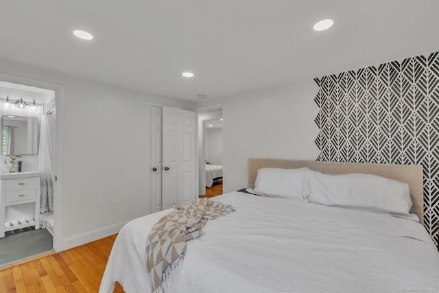 bedroom with recessed lighting, baseboards, ensuite bathroom, and light wood finished floors