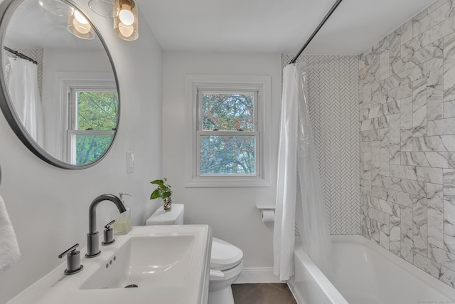 full bath with a sink, toilet, tile patterned floors, baseboards, and shower / tub combo