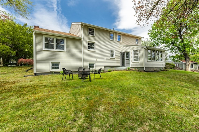 rear view of property with a lawn, a chimney, and entry steps
