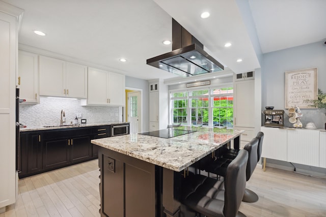 9 Baldwin Dr, Farmington, CT 06032 - kitchen featuring a sink, black electric stovetop, white cabinetry, a breakfast bar area, and light wood-type flooring