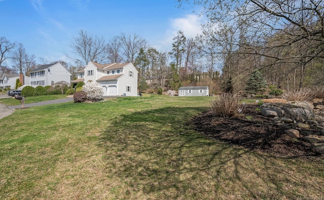 view of grassy yard with a garage, a residential view, and an outbuilding