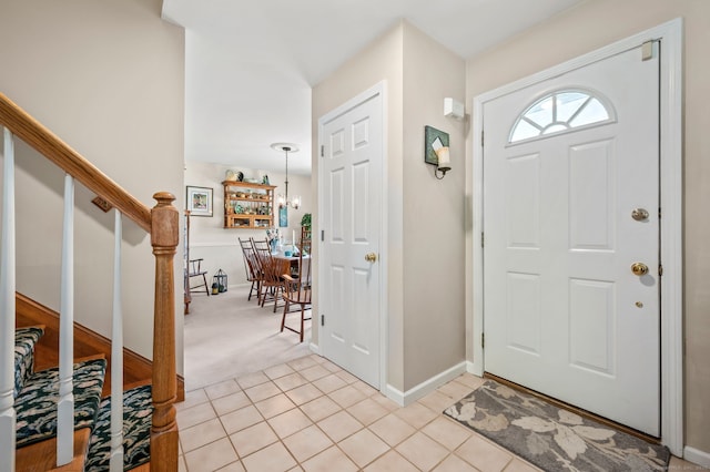 entryway with stairway, light colored carpet, baseboards, and light tile patterned floors