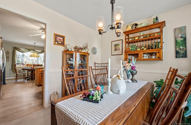 dining area featuring ceiling fan, a chandelier, a baseboard heating unit, and light wood-style flooring