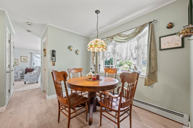 dining room with ornamental molding, baseboard heating, light wood-style flooring, and baseboards