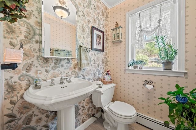half bathroom featuring ornamental molding, wallpapered walls, a baseboard heating unit, toilet, and wood finished floors