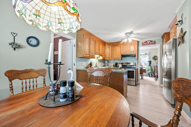 dining room featuring ceiling fan, light wood finished floors, and crown molding
