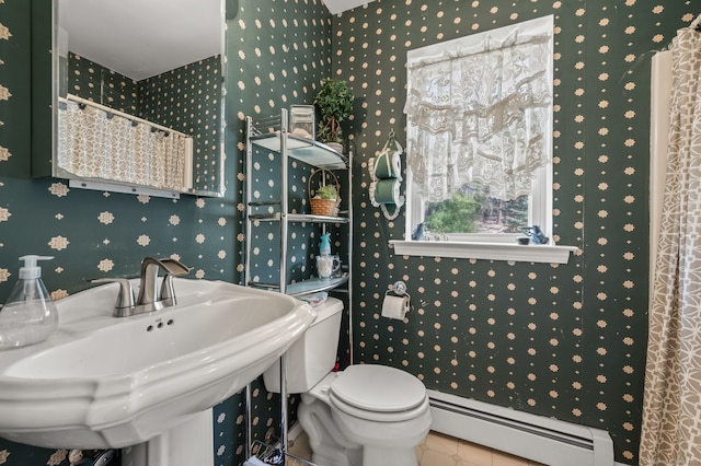 bathroom with a baseboard heating unit, a sink, wallpapered walls, toilet, and tile patterned flooring