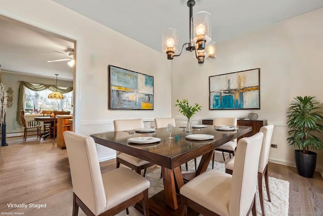 dining area featuring a chandelier, wood finished floors, ceiling fan, and baseboards